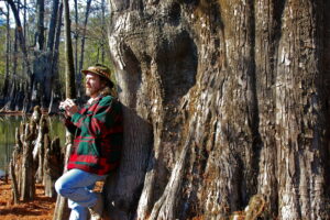 Author Keith Sutton stands beside a massive cypress tree on a lake within White River National Wildlife Refuge in Arkansas. Trees this size can still be found in many of wetlands around the country.