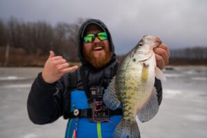 An elated Matt Waldron hoists a giant white crappie caught through the ice near the Twin Cities in Minnesota. Many hours go into the few rare bites that produce big fish. (Photo courtesy Adam Bartusek)