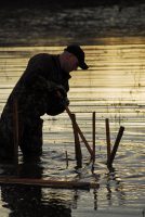 During the winter when his local lake levels are lowered, Shawn Hines dons waders to drive stakes into the bottom. He will return after lake levels rise in the spring and likely find crappie hiding among his stakes. (Photo: Richard Hines)
