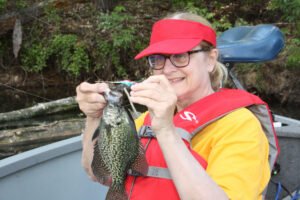 Marilyn Black admires a hand-tied jig that was fished beneath a bobber to catch springtime Black Crappies.
