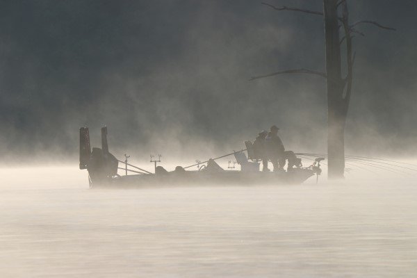 Silhouette of crappie fishermen spider rigging during an early morning fog